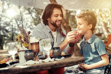 Joyful positive man caring about his young son