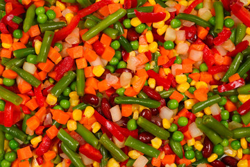 Sliced vegetables, corn, beans, peas, carrots, sweet peppers background.