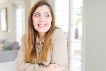 Beautiful young woman at home smiling looking side and staring away thinking.
