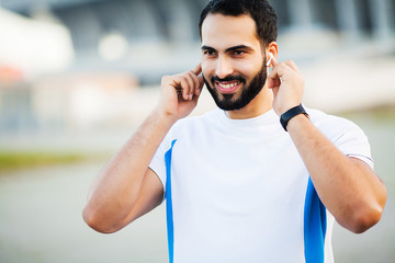 Fototapeta premium Sport man using headphones for listening music on morning run in park
