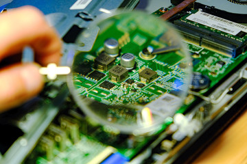 The motherboard is magnified through a magnifying glass. Hardware upgrades computer processor of...