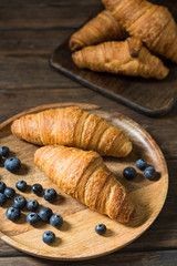 Croissants in a wooden plate on a wooden table. Rustic style