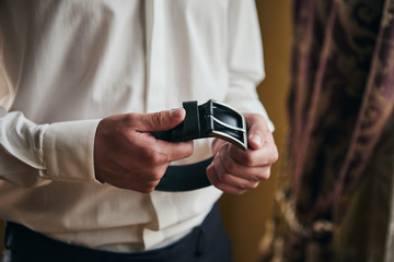 Businessman putting on a belt, fashion and clothing concept,groom getting ready in the morning before ceremony