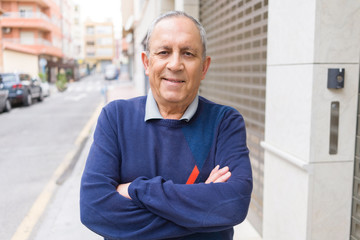 Handsome middle age senior man smiling cheerful, happy and positive with crossed arms at the city town