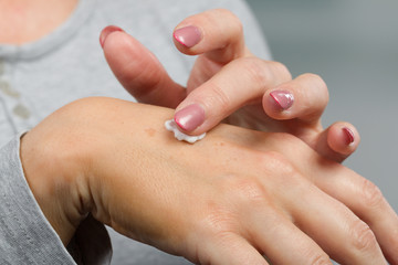 Close up of applying skin cream on female hand