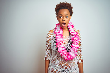 Young african american woman with afro hair wearing flower hawaiian lei over isolated background afraid and shocked with surprise expression, fear and excited face.