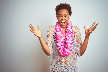 Young african american woman with afro hair wearing flower hawaiian lei over isolated background...