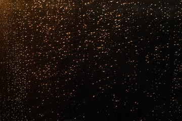 Fototapeta na wymiar Rain drops on window in sunset lights defocused.