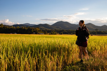 Beautiful traveler woman with backpack on rice fields in Thailand