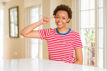 Young beautiful african american woman at home Smiling pointing to head with one finger, great idea or thought, good memory