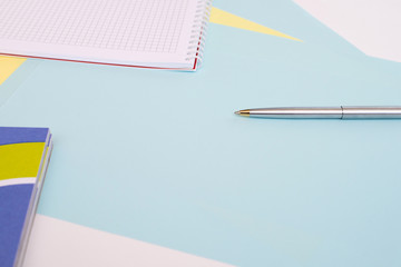 ballpoint pen lies on sheets of blue and yellow paper next to the notebook, white background, layout, Flatley