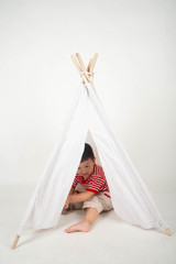Little Asian toddler boy sit in the tent at home with happy smile