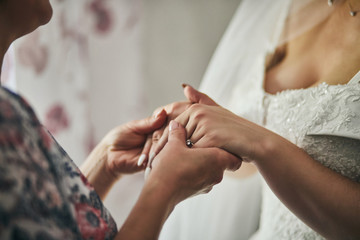 Bride on wedding day holding her mother's hands. Concept of relationship between moms and daughters
