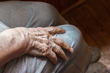 wrinkled hand of an elderly woman with clearly visible veins reaching out forward lying on her knee. Aging and care for the elderly concept..