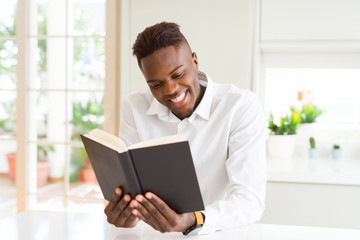 Young african man reading a book, studying for univeristy smiling confident