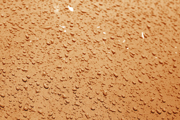 Water drops on car surface in orange tone.