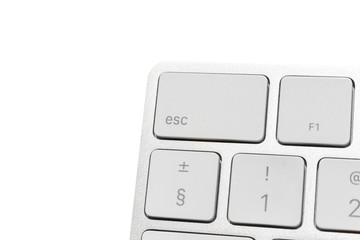Big escape key in the corner of white wireless computer keyboard. aluminum keyboard isolated on white. Focus on escape button.