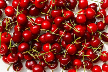 Naklejka na ściany i meble red summer sweet cherry scattered on a white table, texture with view from above. cherry just gathered in the garden.