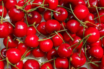 a heap of red summer sweet cherries scattered on table, texture with view from above. Major commercial cherry orchards in Europe are in Turkey, Italy, Spain and other Mediterranean regions.
