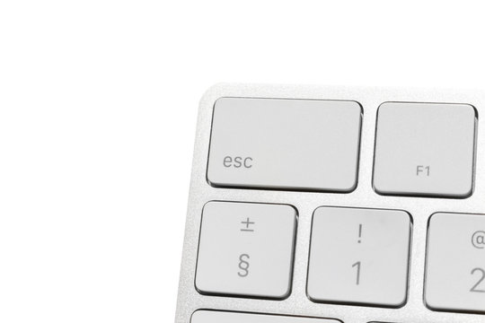 Big escape key in the corner of white wireless computer keyboard. aluminum keyboard isolated on white. Focus on escape button.