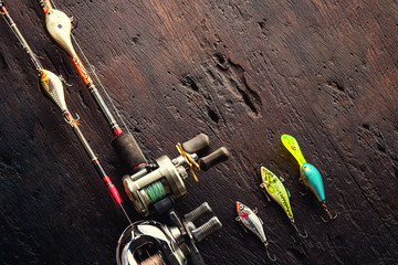 Fishing lures, hooks and accessories on darken wooden background.Top view.