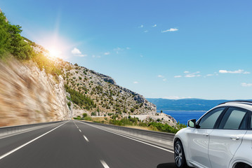 White car rushes along the road to the sea. Motion blur effect.