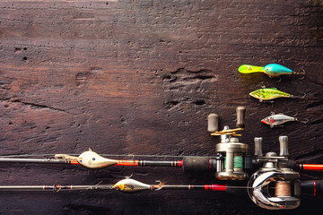 Fishing lures, hooks and accessories on darken wooden background.Top view.