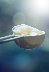 Closeup of white capsules on blue abstract background. pills in the spoon. Pharmaceutical industry. Fresh vitamin nutrition. Healthcare, medicine. Medical health care. Tablet overdose. Healthy food.