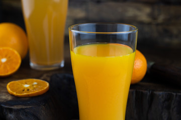Still life photo of orange juice, orange smoothie in a glass on wooden background.