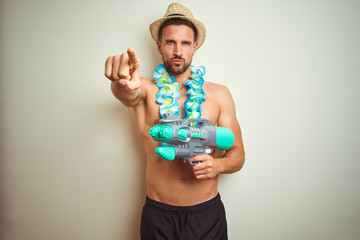 Handsome shirtless man wearing hawaiian lei and water gun over background pointing with finger to the camera and to you, hand sign, positive and confident gesture from the front - Powered by Adobe