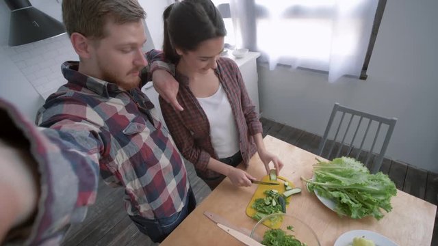 family photo in kitchen, cheerful female with male take selfie photo on smartphone while cooking vegetable salad on dinner for wellness according to diet plan on cuisine table