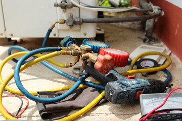 The technician is using tools to check the air conditioner, take a blur