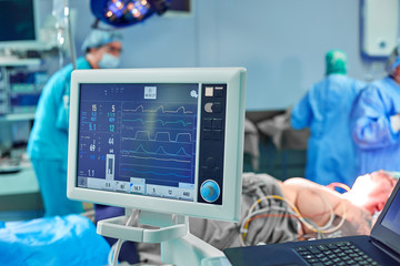 Electrocardiogram in hospital surgery operating emergency room showing patient heart rate with blur...