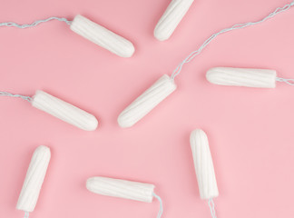 Medical female tampon on a pink background. Hygienic white tampon for women. Cotton swab. Menstruation, means of protection. Tampons on a red background.