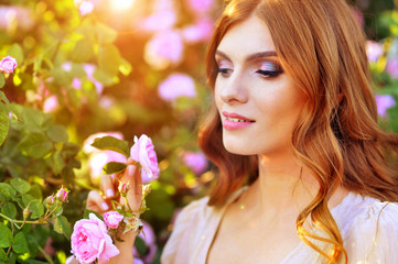 Fototapeta premium Portrait of beautiful young woman posing by rose bush