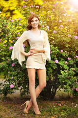 Portrait of beautiful young woman posing by rose bush