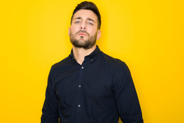 Obraz premium Young handsome man possing and modeling over yellow isolated background