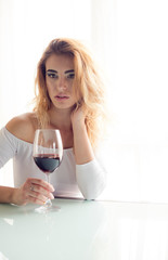 Young beautiful woman with glass of red wine on light background