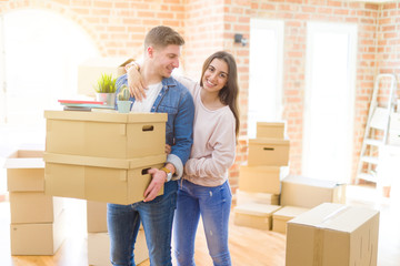 Beautiful young couple smiling in love holding cardboard boxes, happy for moving to a new home