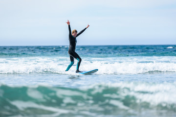Surfer girl surfing with surfboard on waves in Atlantic ocean.
