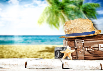 Fototapeta na wymiar Summer retro suitcase on desk and beach landscape 