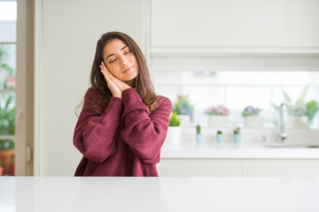 Fototapeta premium Young beautiful woman at home sleeping tired dreaming and posing with hands together while smiling with closed eyes.