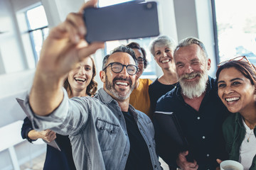 Multiracial group of people taking selfie at office