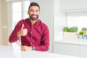 Fototapeta premium Handsome hispanic business man doing happy thumbs up gesture with hand. Approving expression looking at the camera showing success.