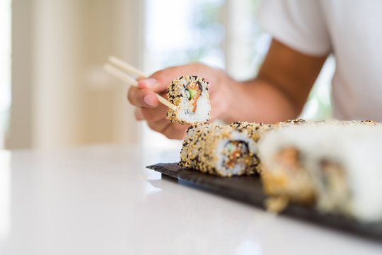 Close up of colorful sushi asian food, man hands holding sushi pieces using chopsticks