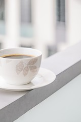 Porcelain cup of black coffee on a windows background. Copy space