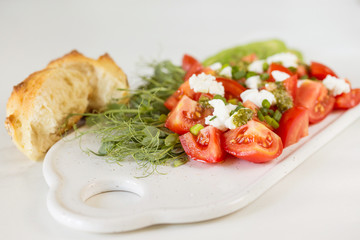 Breakfast salad with tomatoes, avocado, bun, pea sprouts, and coffee