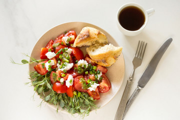 Breakfast salad with tomatoes, avocado, bun, pea sprouts, and coffee