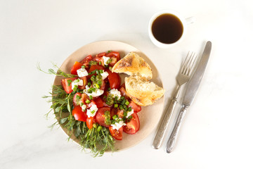 Breakfast salad with tomatoes, avocado, bun, pea sprouts, and coffee