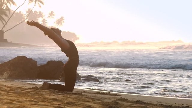 lady silhouette stretches body standing on knees in Core-Supported Backbending Sequence pose against boundless ocean in morning slow motion. Concept health wellness lifestyle